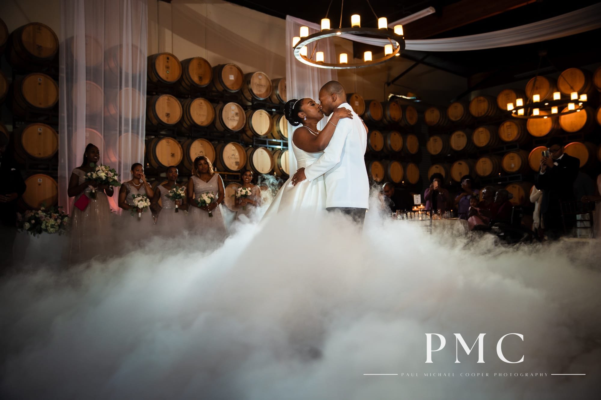 A bride and groom kiss during their first dance in the barrel room at their wedding reception.