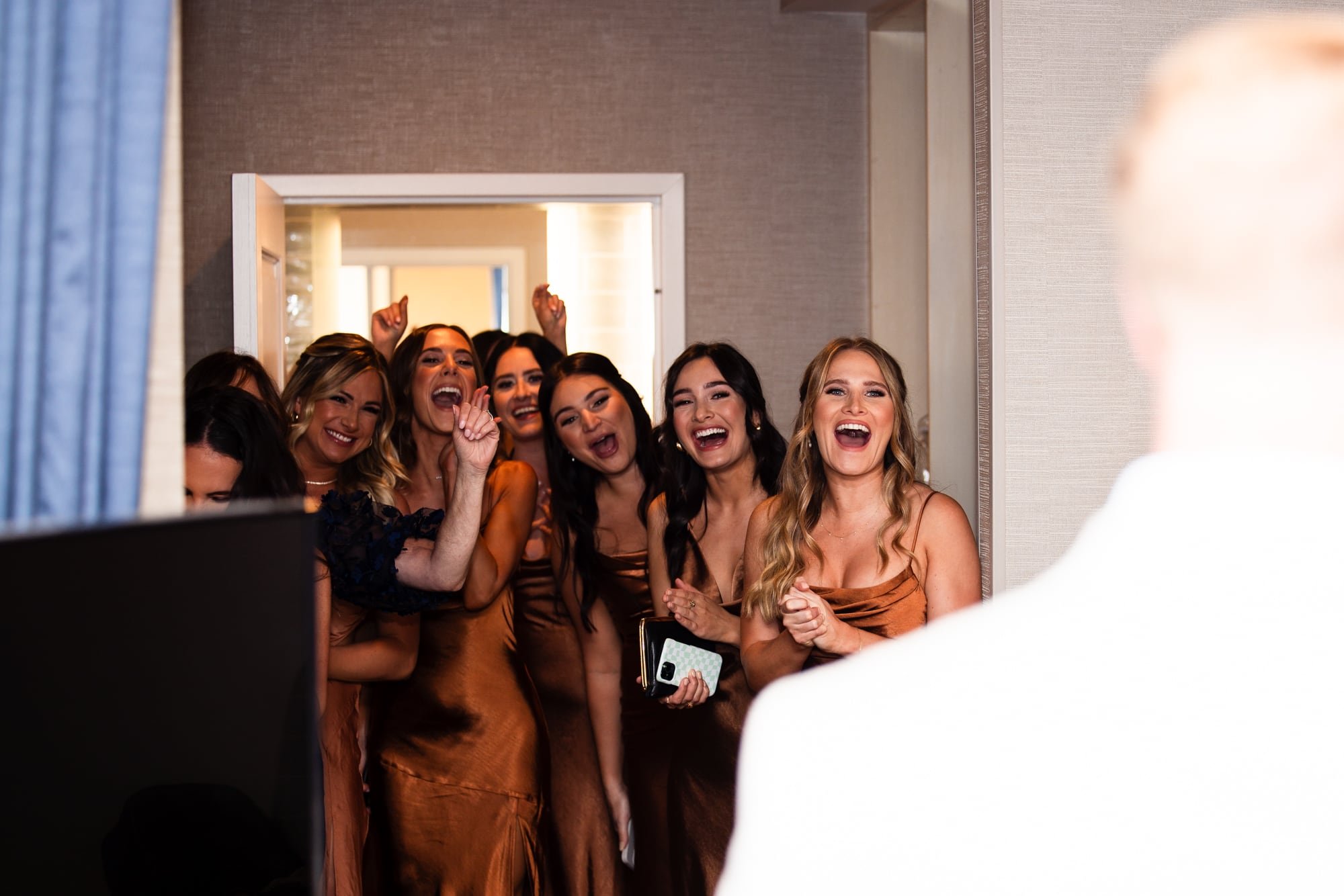 Bridesmaids smile and cheer at seeing the bride and groom after their balcony First Look.