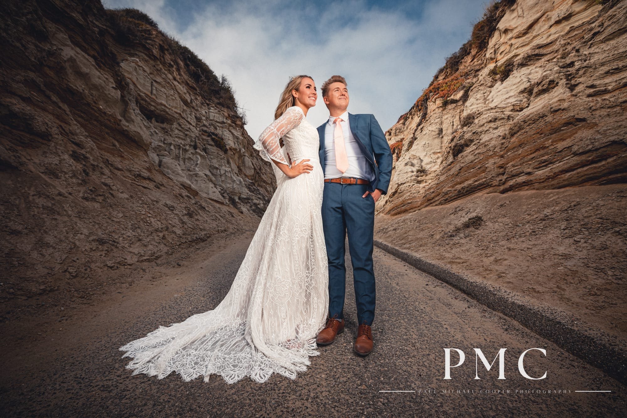 A bride and groom smile with each other, framed in a stunning San Clemente canyon.
