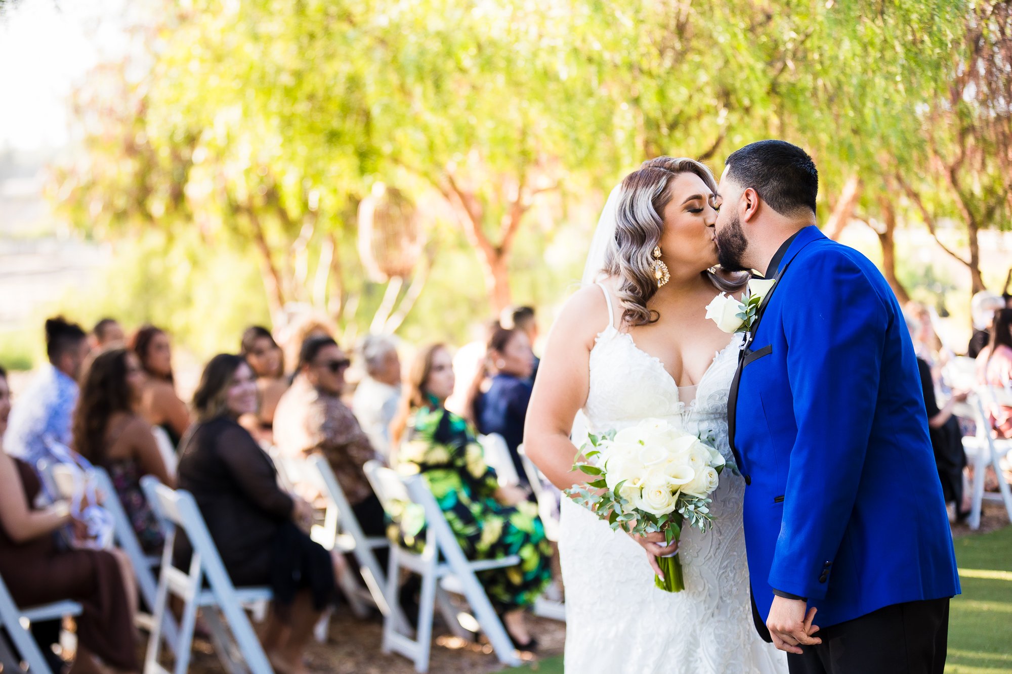Bride and Groom kiss as they walk down the aisle together after their wedding ceremony at La Hacienda Outdoor Venue