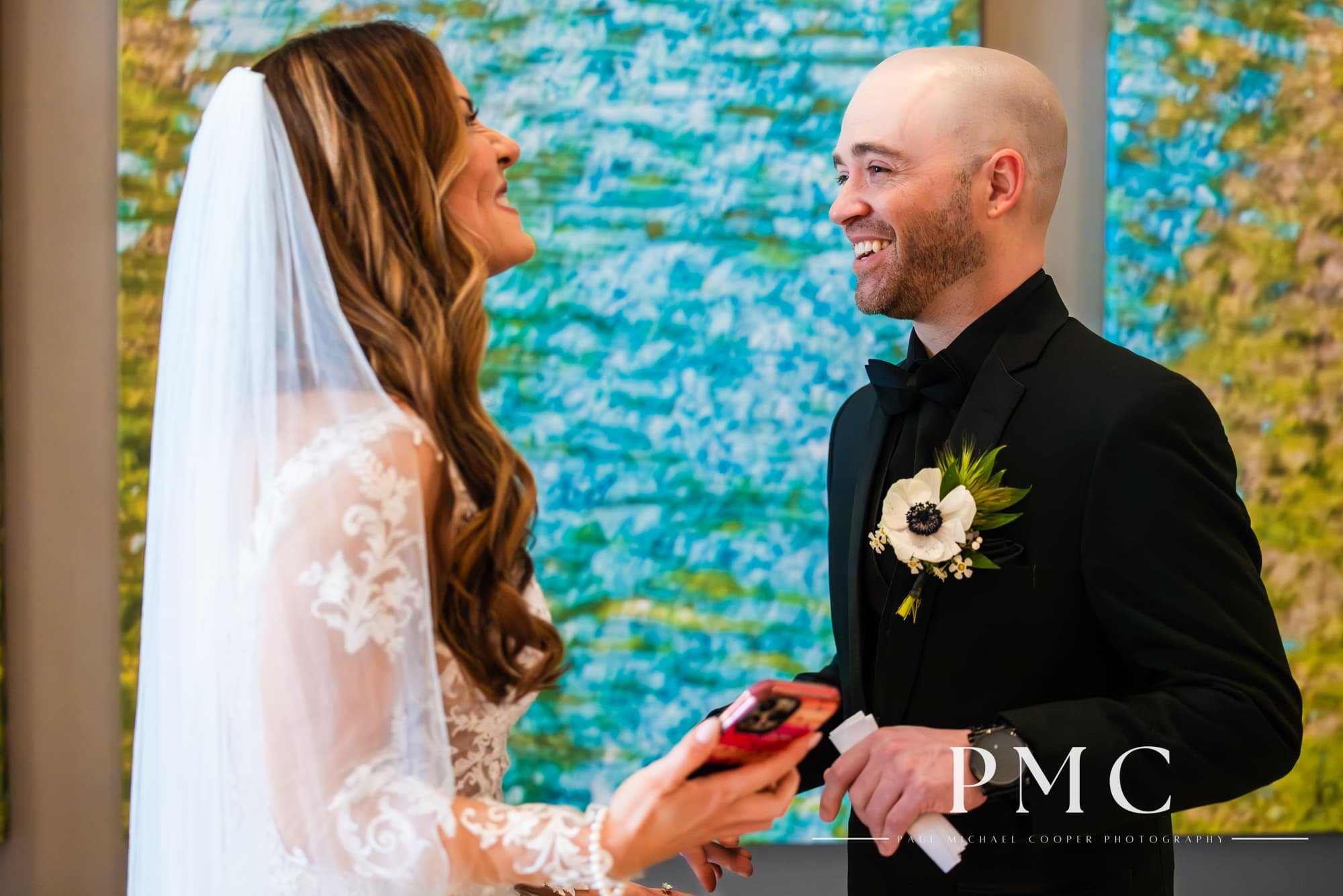 A groom smiles happily at his bride during their wedding day First Look in the lobby of the Hotel Indigo in Downtown San Diego.