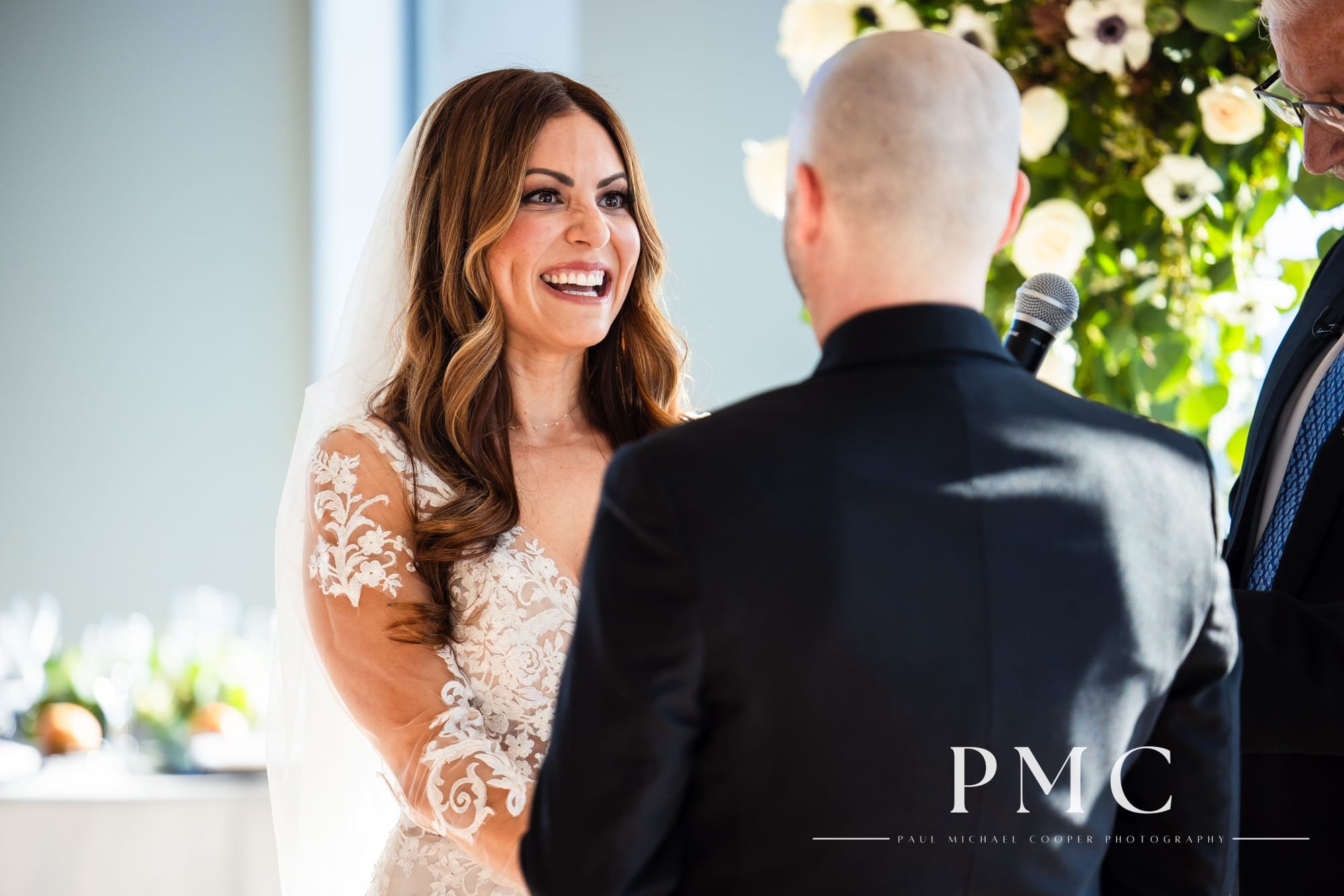 A bride smiles happily at her groom during their wedding ceremony at the Ultimate Skybox in Downtown San Diego.