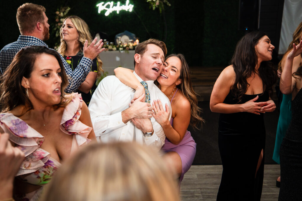 A wedding guest and her plus-one dance and sing together on the dance floor of a spring wedding reception.