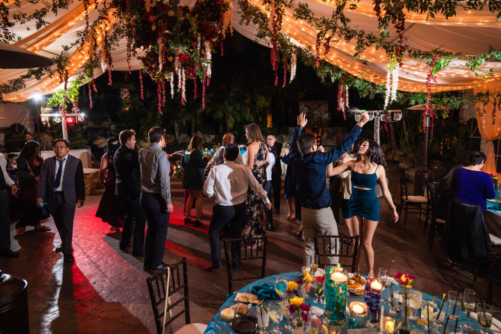 Wedding guests dance at a vibrant tented wedding reception.