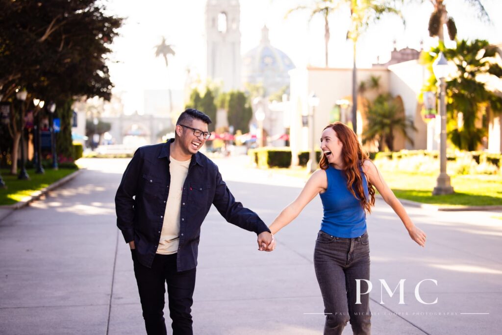 A couple laughs and hold hands during their Balboa Park engagement session.