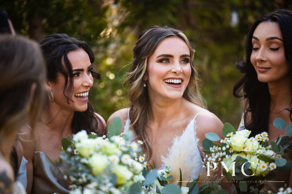 A bride smiles and laughs with her bridesmaids on her spring wedding day.