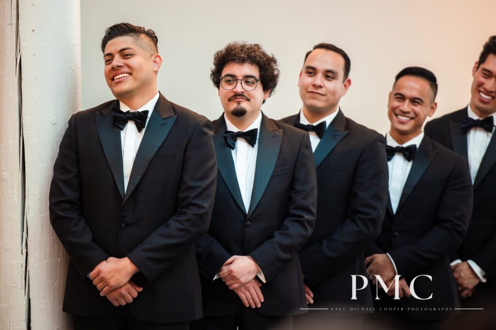 Groomsmen smile as they watch a chapel wedding ceremony unfold.