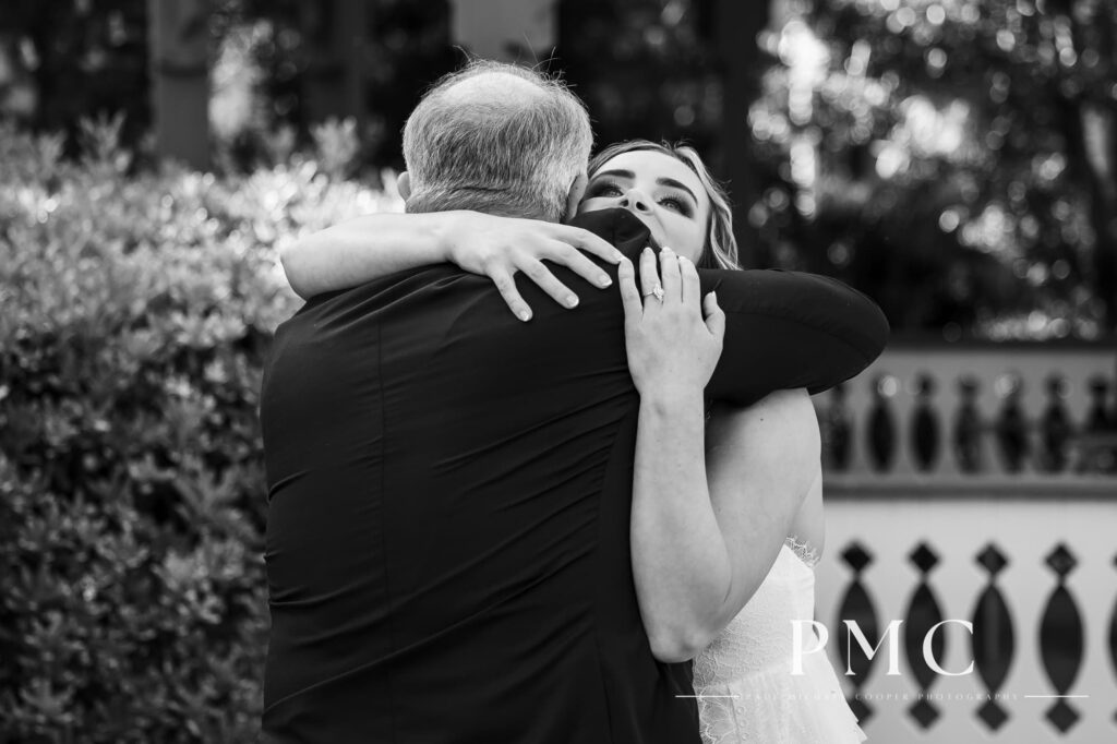 An emotional black-and-white wedding photo of a bride hugging her father on her wedding day.