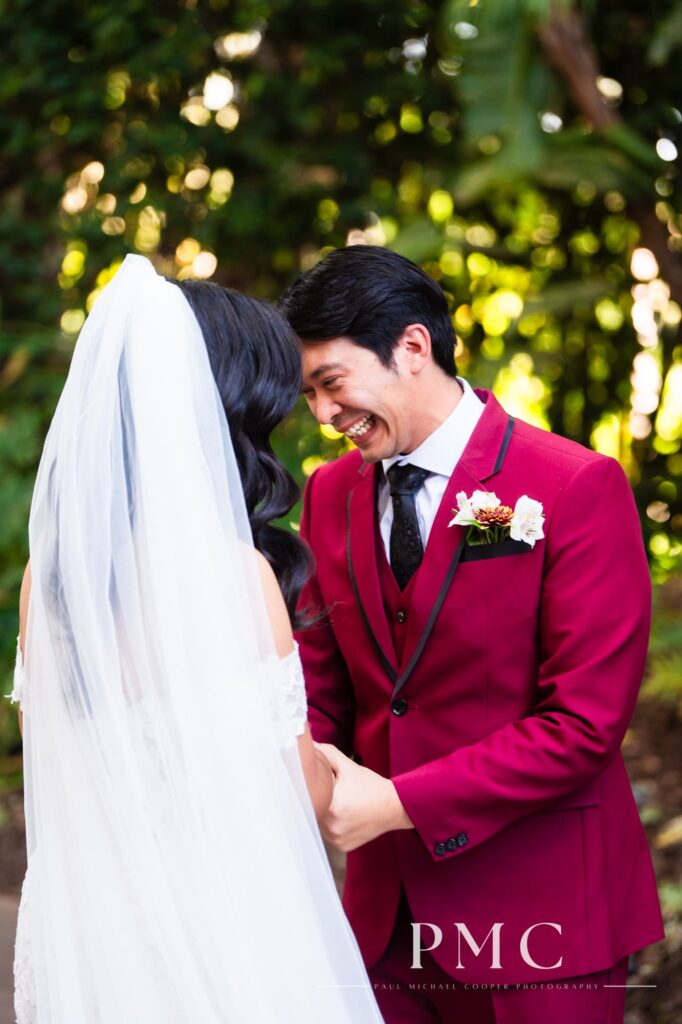 An excited groom smiles emotionally during their wedding first look.