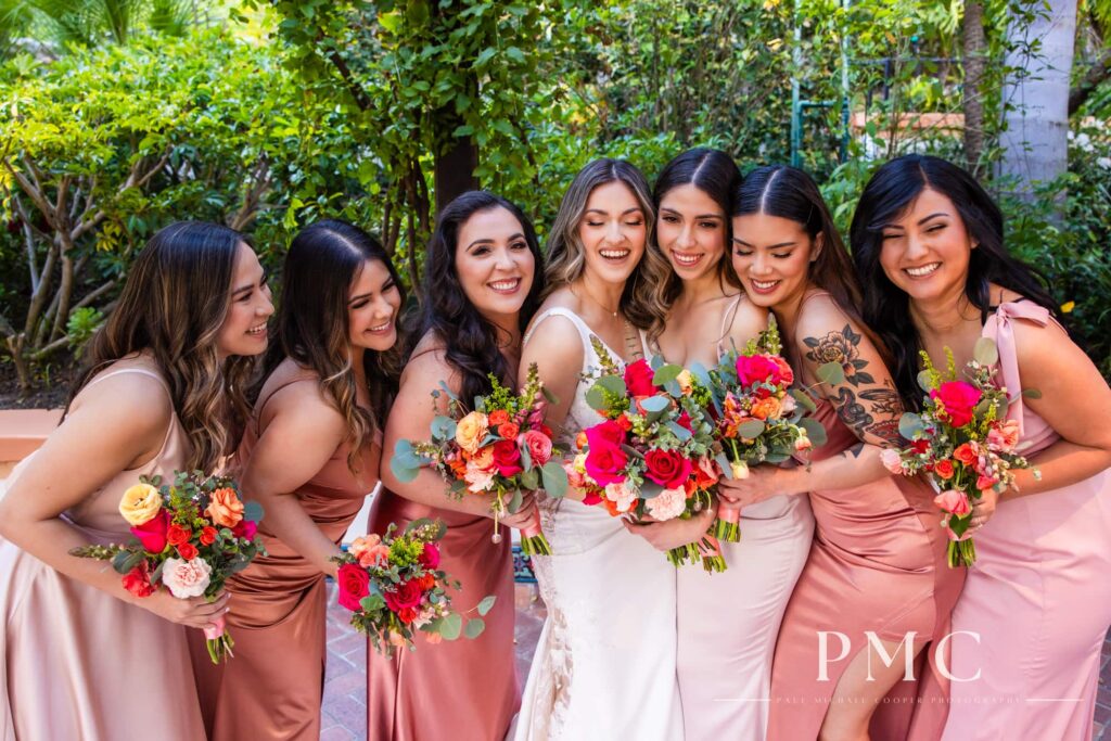 A bride and her bridesmaids smiling and laughing with each other at Rancho Las Lomas wedding venue.