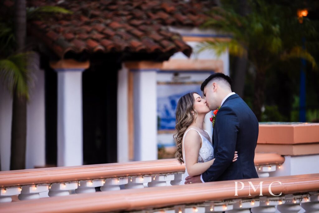 A bride and groom embrace each other and kiss on Rancho Las Lomas wedding venue's iconic bridge.