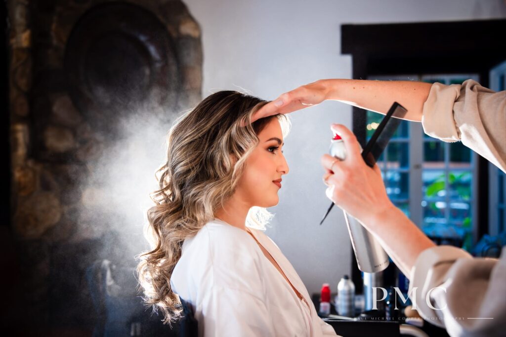 A bride having her hair and makeup done on her wedding day.