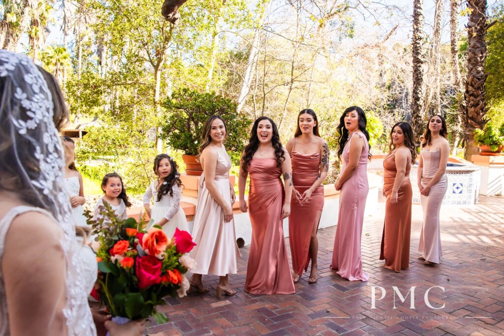 A bride shares a first look reveal with her bridesmaids on her outdoor spring wedding day.
