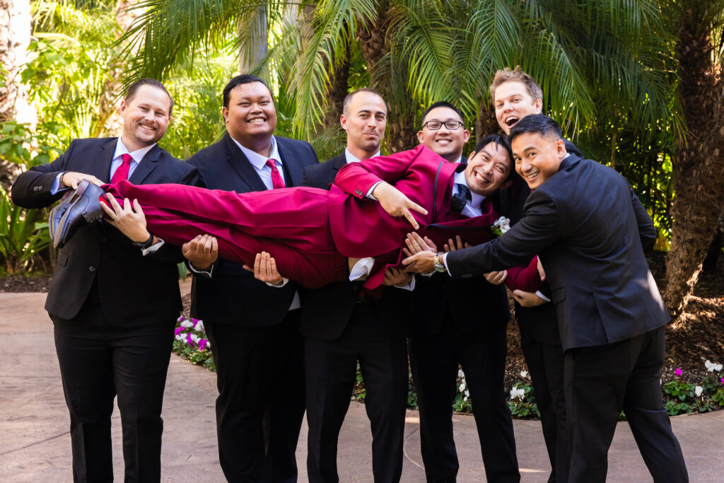 Groomsmen holding up the groom and smiling for the camera at his wedding at Grand Tradition Estate and Gardens in Fallbrook, Southern California.