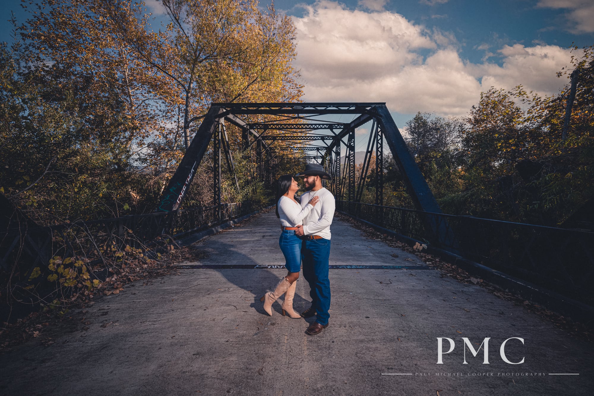 A cinematic portrait of a couple embracing on a bridge during their fall engagement session.