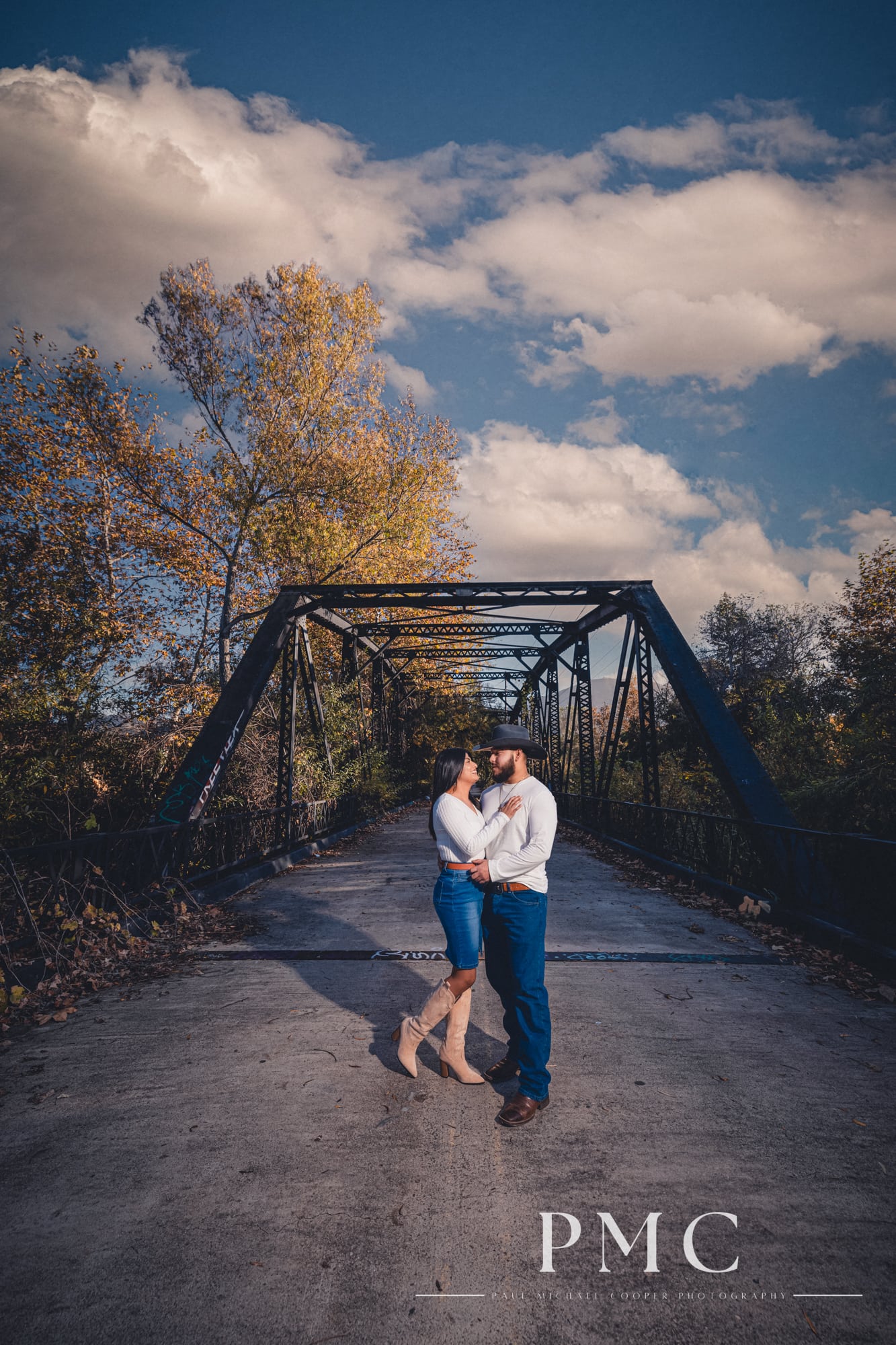 A cinematic portrait of a couple embracing on a bridge during their fall engagement session.