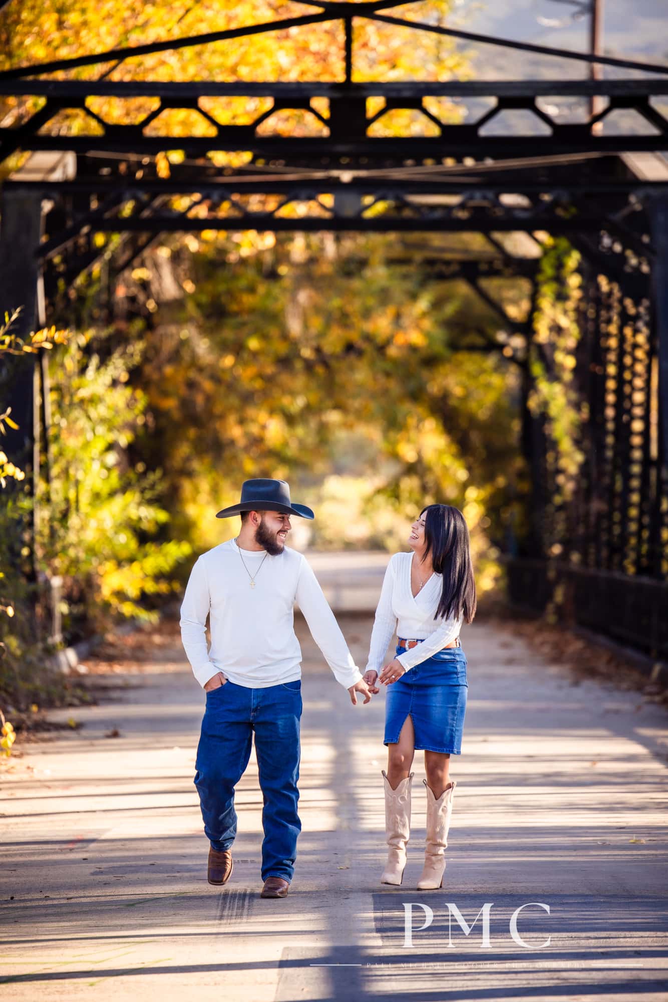 A couple smiles and hold hands in their fall engagement photos.