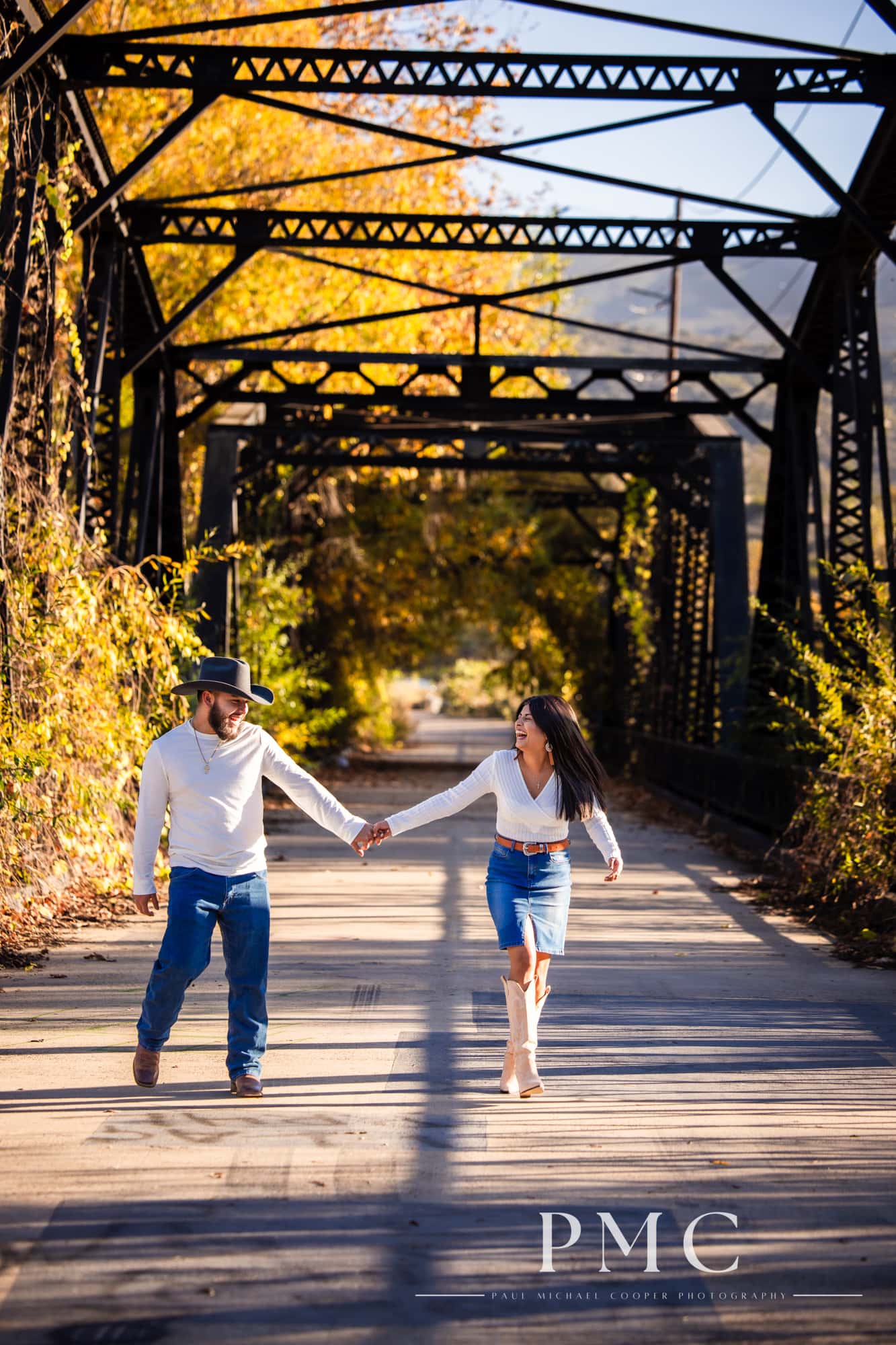 A couple smiles and hold hands in their fall engagement photos.