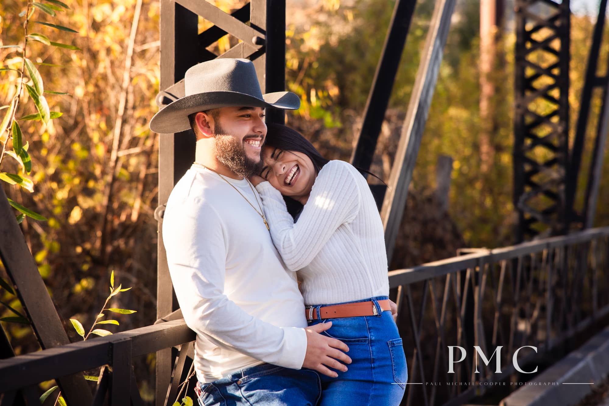 A couple smiles and laughs in their fall engagement photos.
