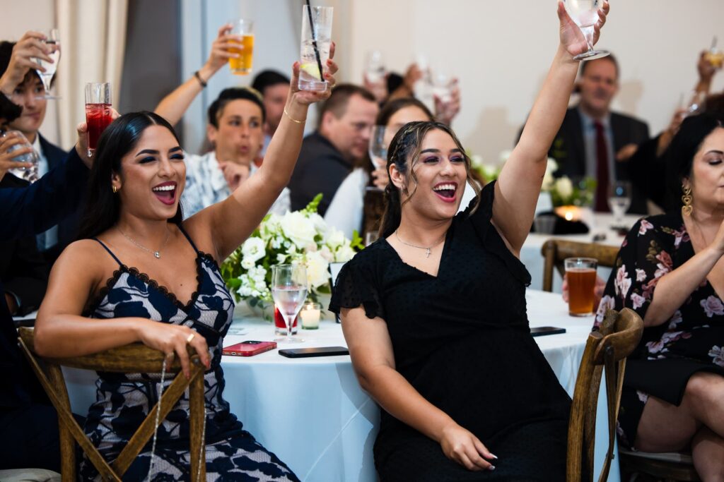 Wedding guests raise their glasses and cheer.