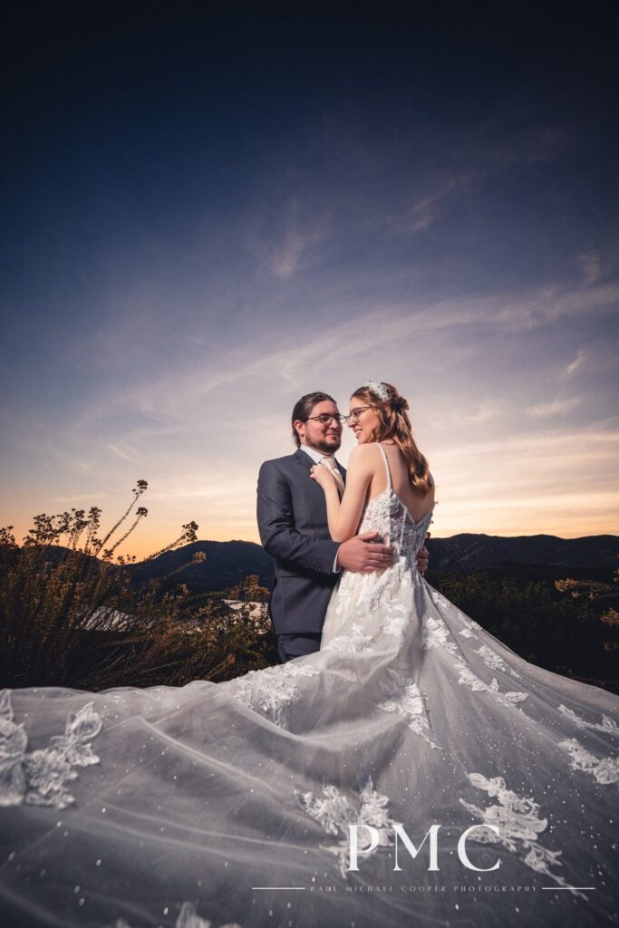 A bride and groom embrace each other at sunset at their fall valley wedding on a private estate in Escondido.