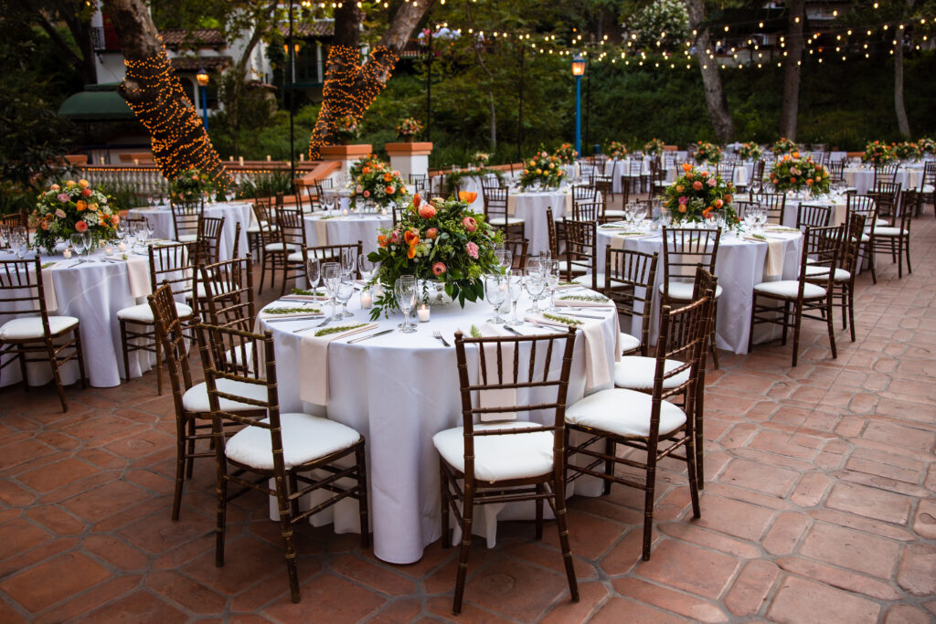 Outdoor wedding reception tables and florals under string lights at Rancho Las Lomas.