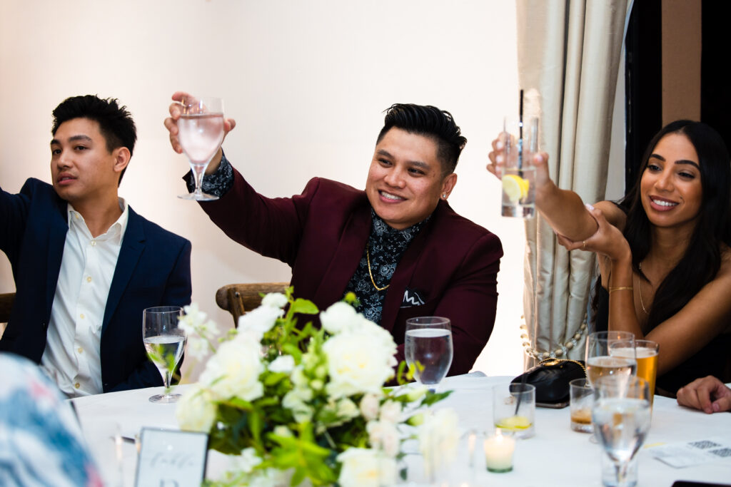 Wedding guests smile and raise their glasses in a toast to the newlyweds at Avensole Winery in Temecula.