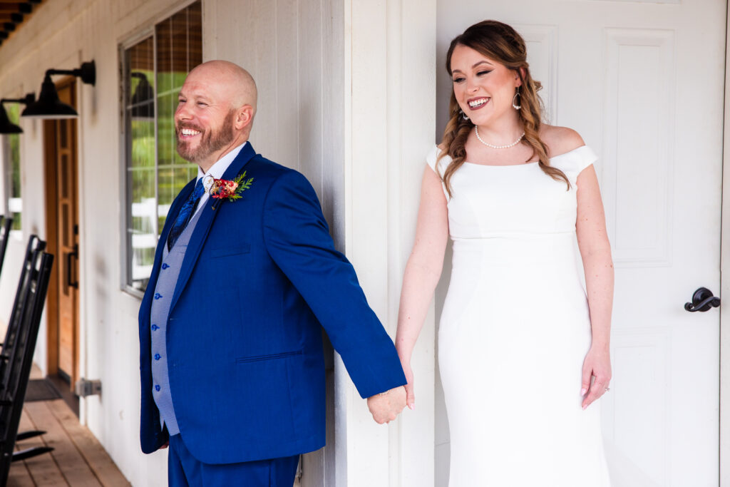 A bride and groom hold hands around a corner, sharing a First Touch on their winter wedding day at Lake Oak Meadows in Temecula.