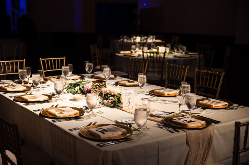 A mix of rectangular and round tables decorated with linens and florals at a wedding reception as the wedding seating arrangement.