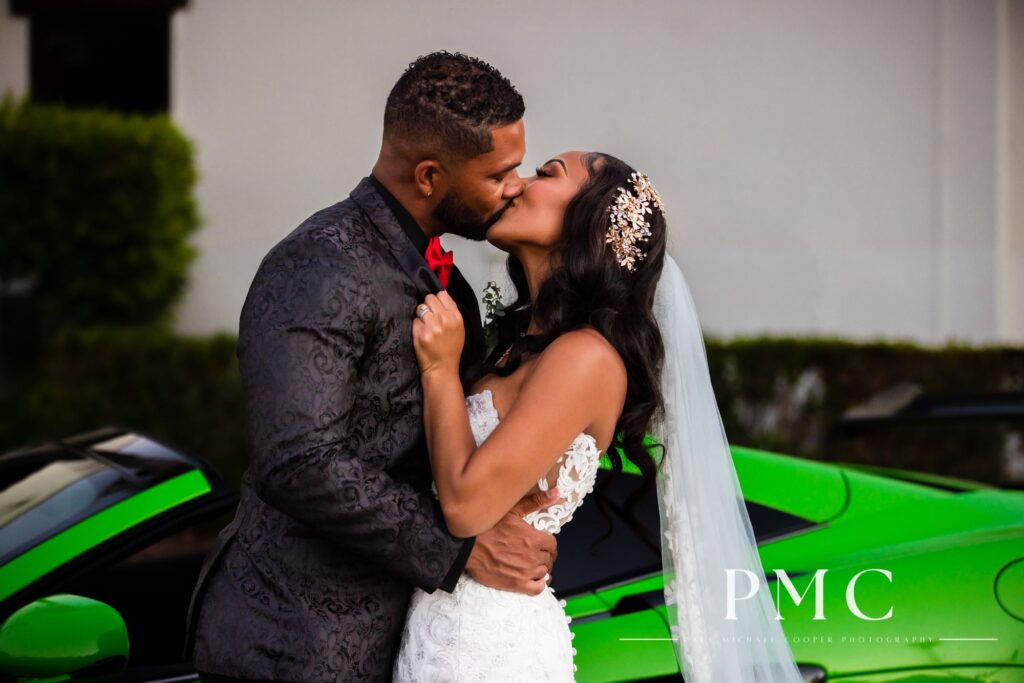 A bride and groom share a wedding day kiss in front of a bright green McLaren wedding car.