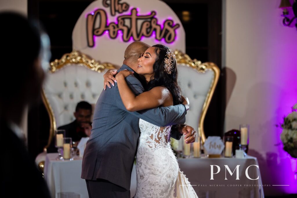 A bride shares a hug during father-daughter dance at her indoor reception at Fallbrook Estate by Wedgewood Weddings.