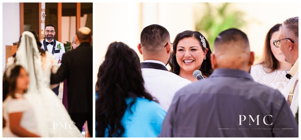 A groom smiles at his bride as she comes down the aisle at their Mexican Catholic mariachi wedding ceremony.