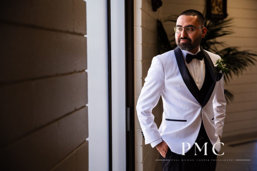 A groom looks out the window before his wedding ceremony at a church in Vista.