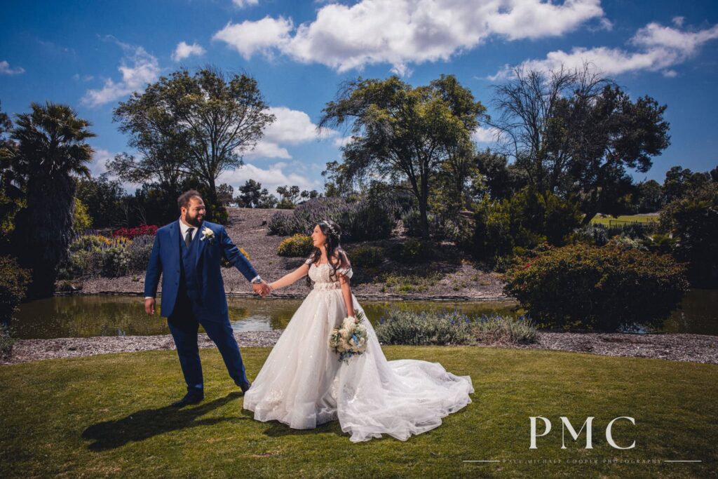 A bride and groom with floral bouquet walk hand in hand among the nature at The Heights Golf Club.