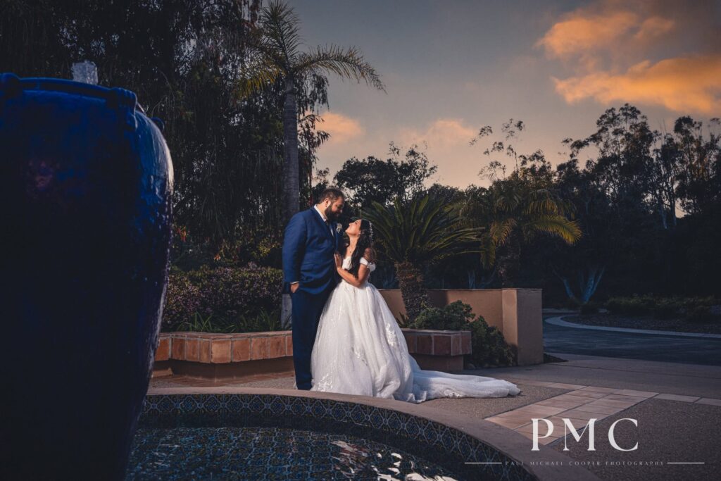 A bride and groom share an embrace  at sunset at the front fountain of The Heights Golf Course.