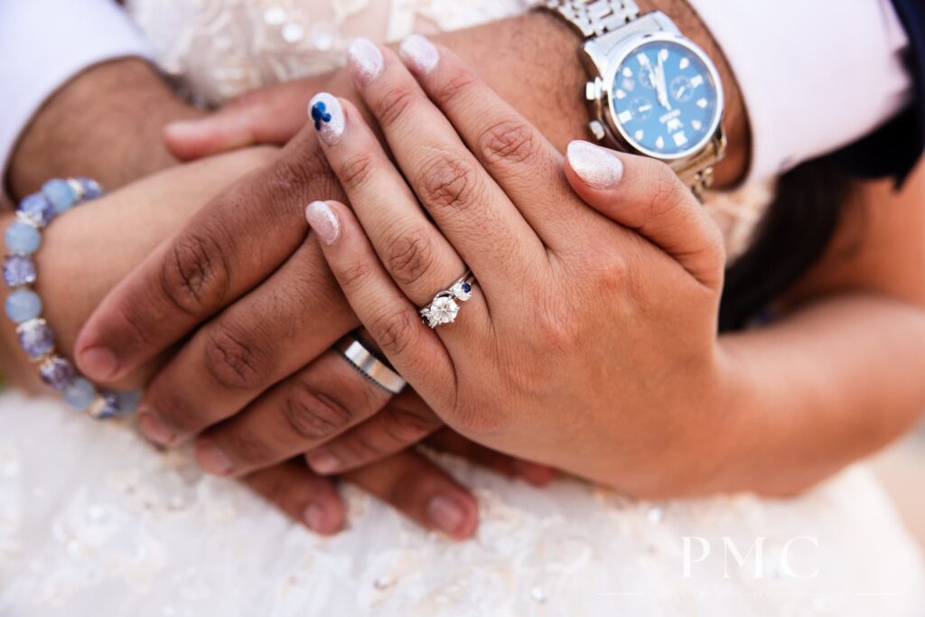 A close-up photo of wedding rings on a bride and groom's hands.