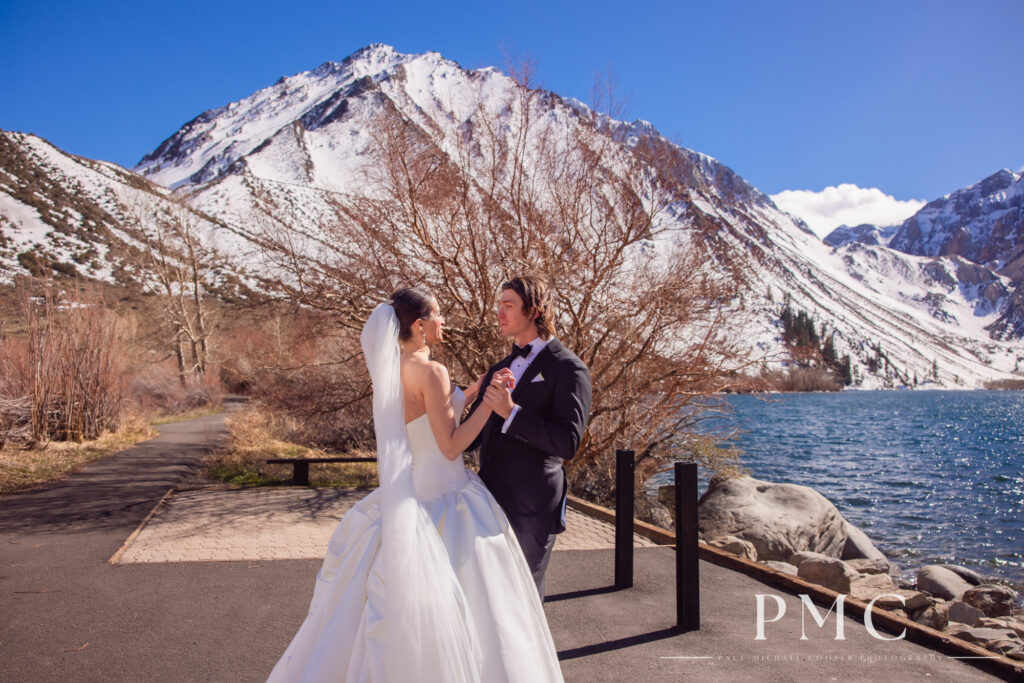 A bride and groom hold hands during their wedding day First Look in front of a mountain at Convict Lake in Mammoth Lakes.