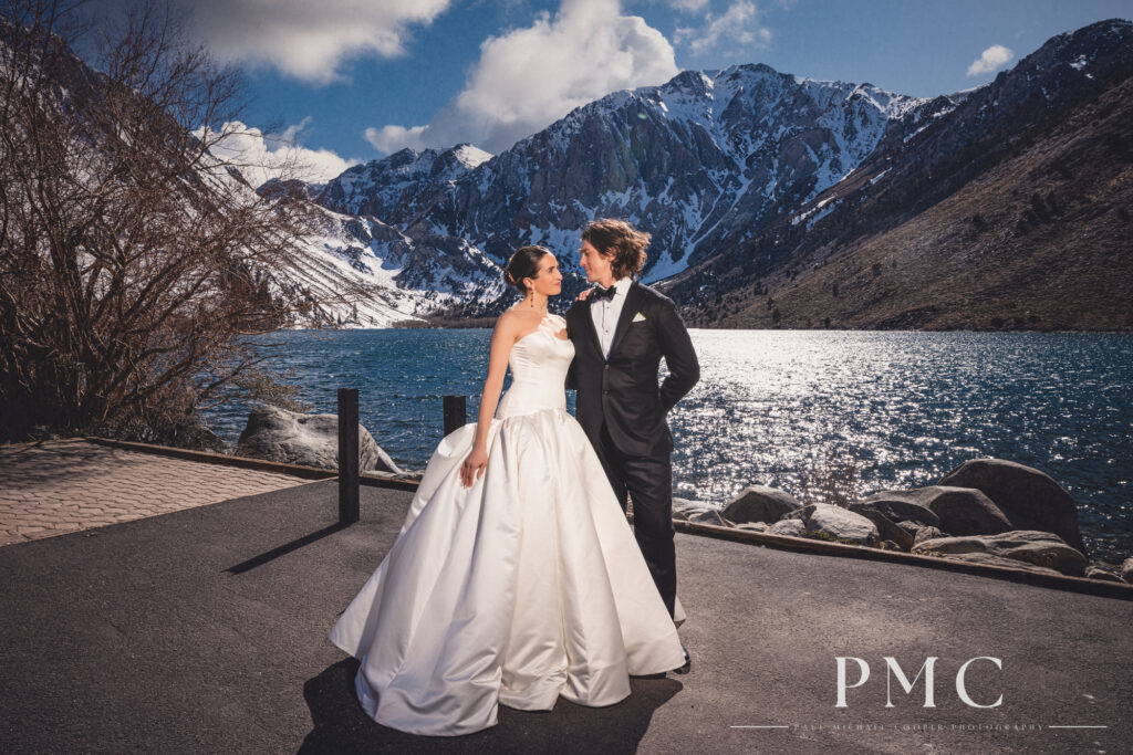 A bride and groom embrace in front of a mountain backdrop at Convict Lake in Mammoth Lakes.