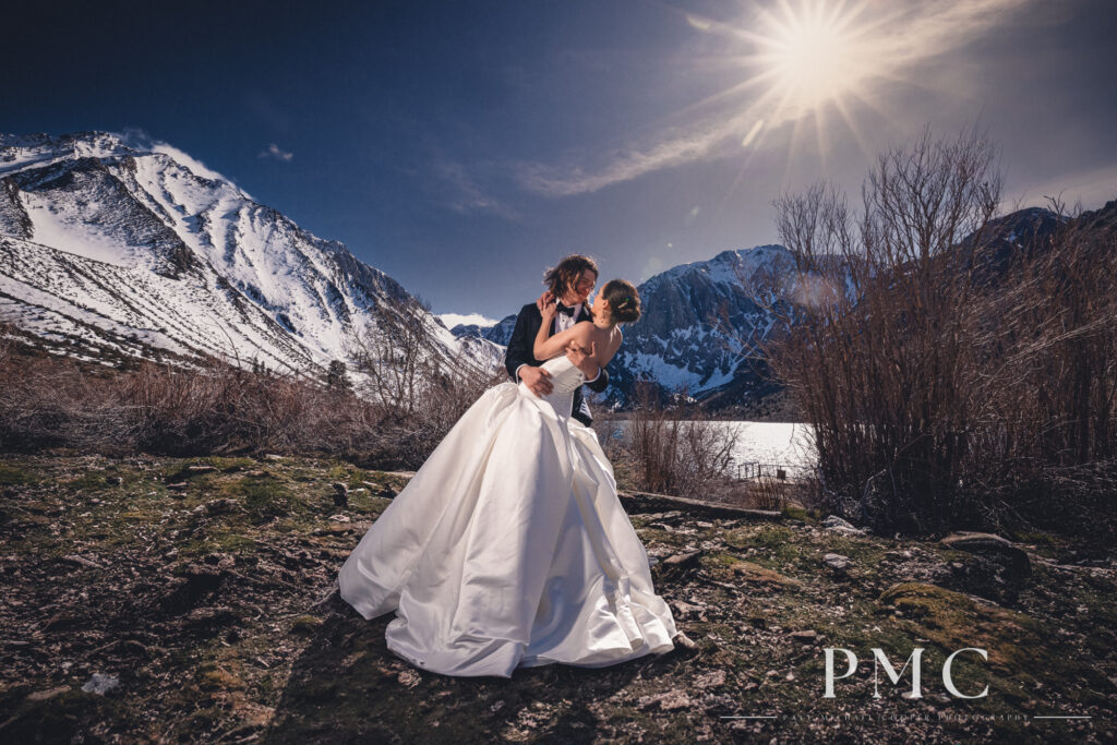 A bride and groom embrace in a dip on their wedding day in front of a mountain landscape at Mammoth Lakes.