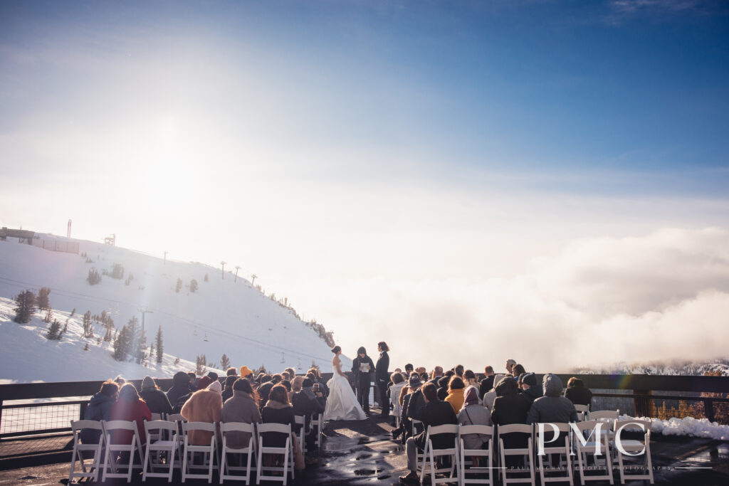 A wide-angle photo of a wedding ceremony taking place on the rooftop of a ski station on Mammoth Mountain.