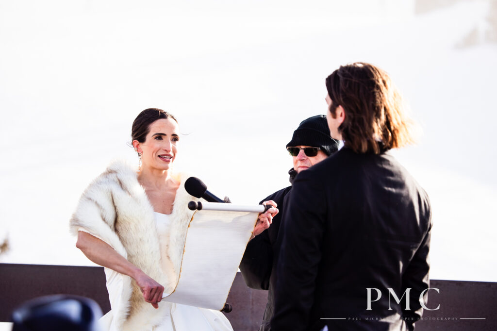 A bride in a fur stole reads her wedding vows from a parchment scroll during her outdoor mountain ceremony in Mammoth.