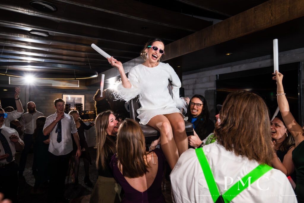 A bride smiles and laughs as she is lifted into the air at her Mammoth Mountain wedding reception.