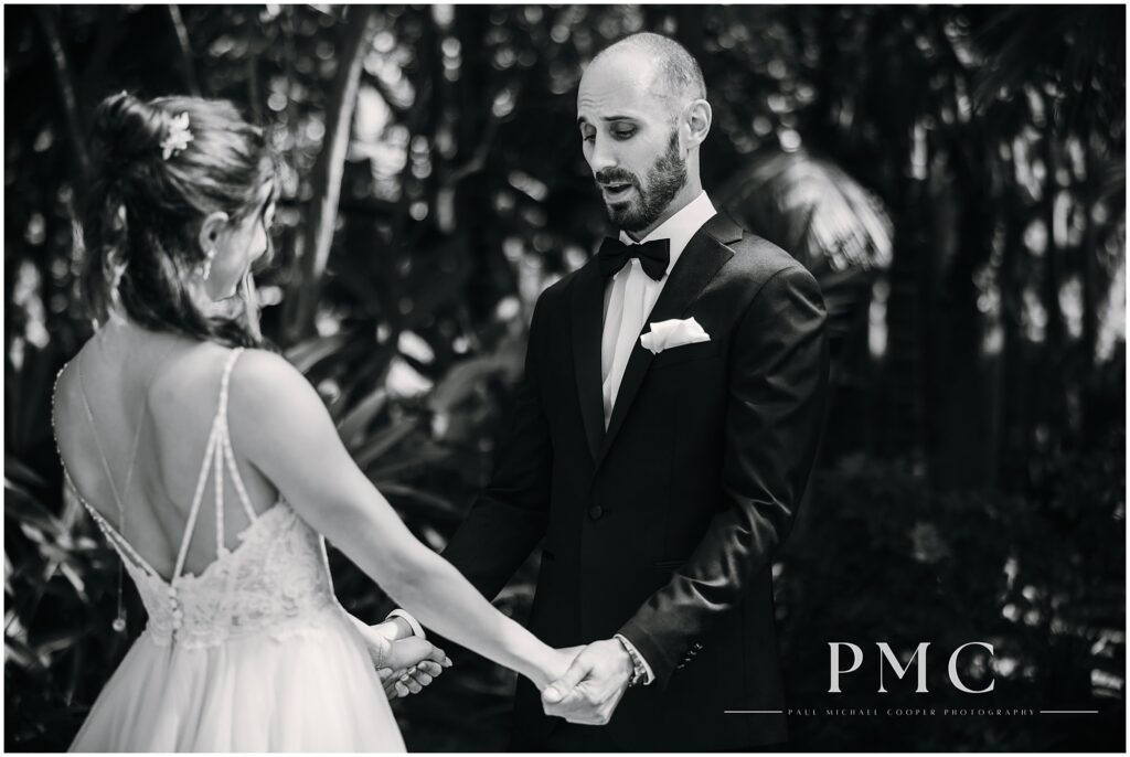 Emotional black and white photo of a groom's expressive reaction to seeing his bride for the first time.