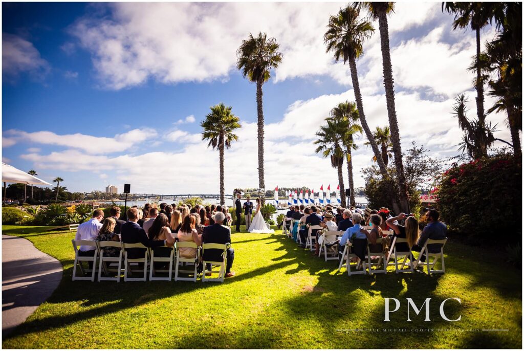 A wide photo of a ceremony at a waterfront wedding venue with a view of Mission Bay.