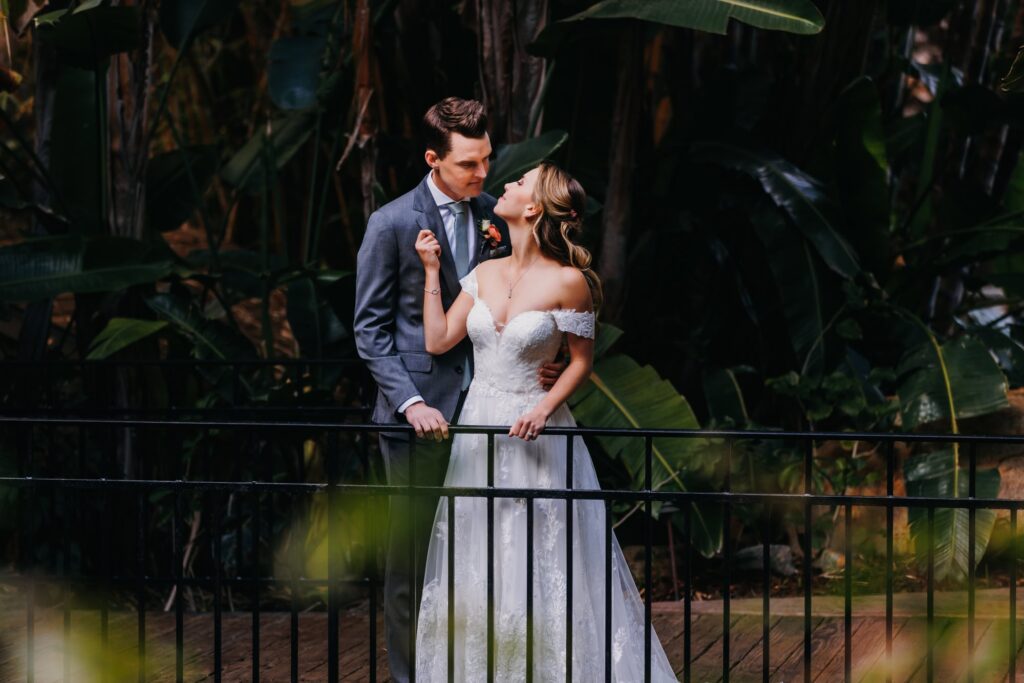 A bride and groom embrace each other amid jungle foliage at Grand Tradition Estate wedding venue.