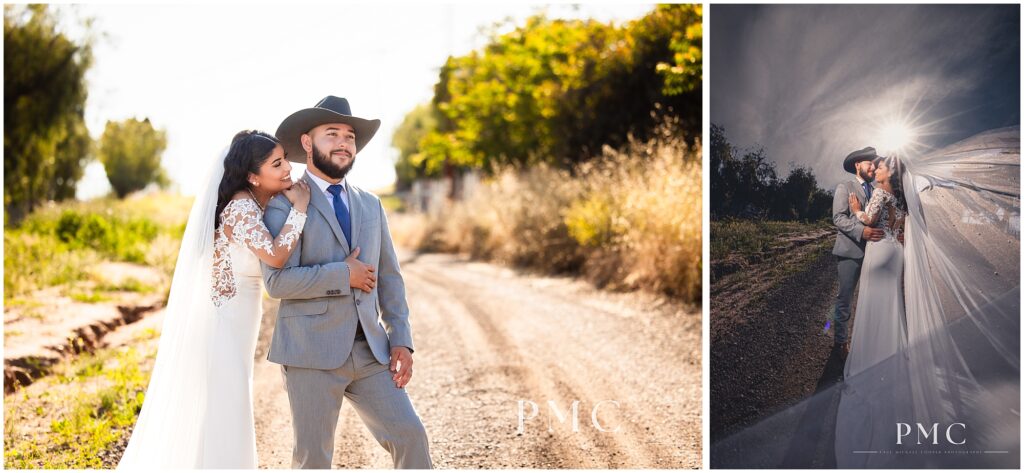 A bride with a long, flowing train and veil and elegant hairpiece dances on a rustic dirt road with her groom, who is wearing a grey suit with cowboy boots and a cowboy hat on their country-style wedding day.