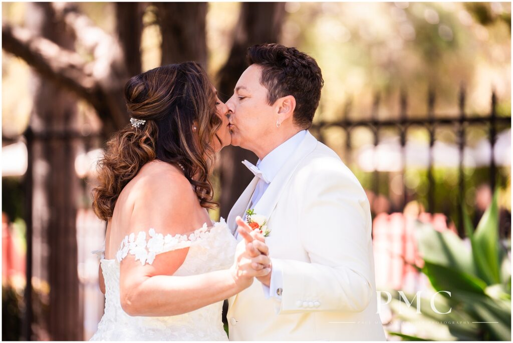 Two brides share a First Look moment on the front lawn of the terracotta, historical Rancho Minerva Wedding Venue in Vista.