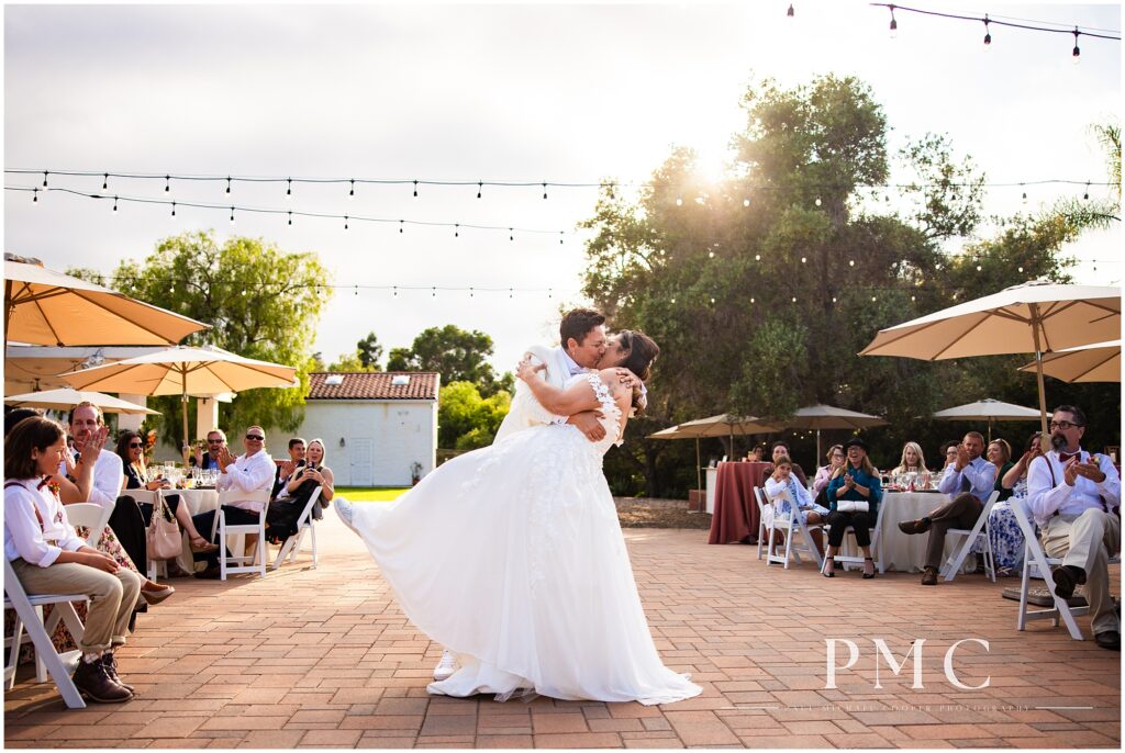 Two brides smile during their choreographed first dance on their summer wedding day at the terracotta Rancho Minerva Wedding Venue.