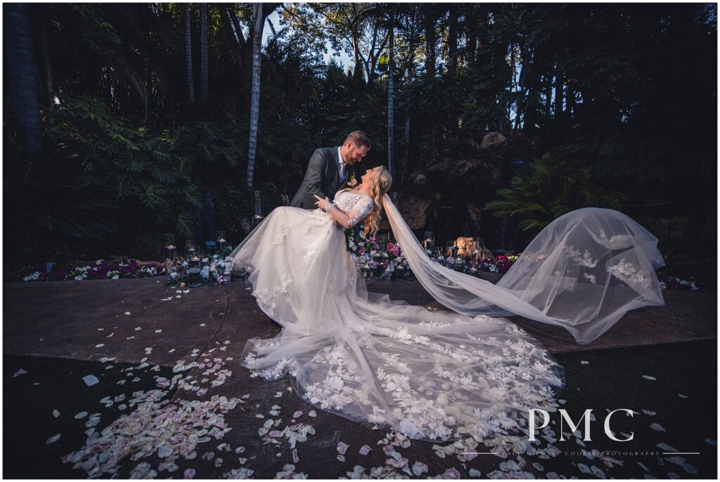 Wedding photo of a bride and groom in a dramatic dip with a sweeping veil at Grand Tradition Estate & Gardens.