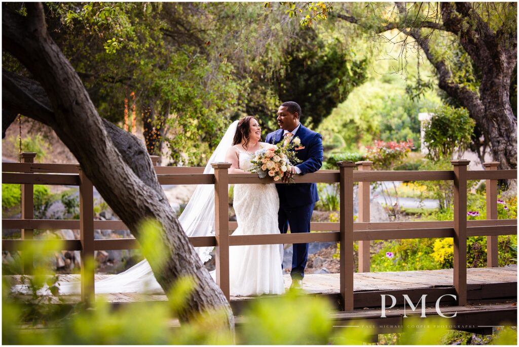 A bride and groom smile at each other on nature-surrounded bridge at Los Willows Wedding Venue in Fallbrook, Southern California.